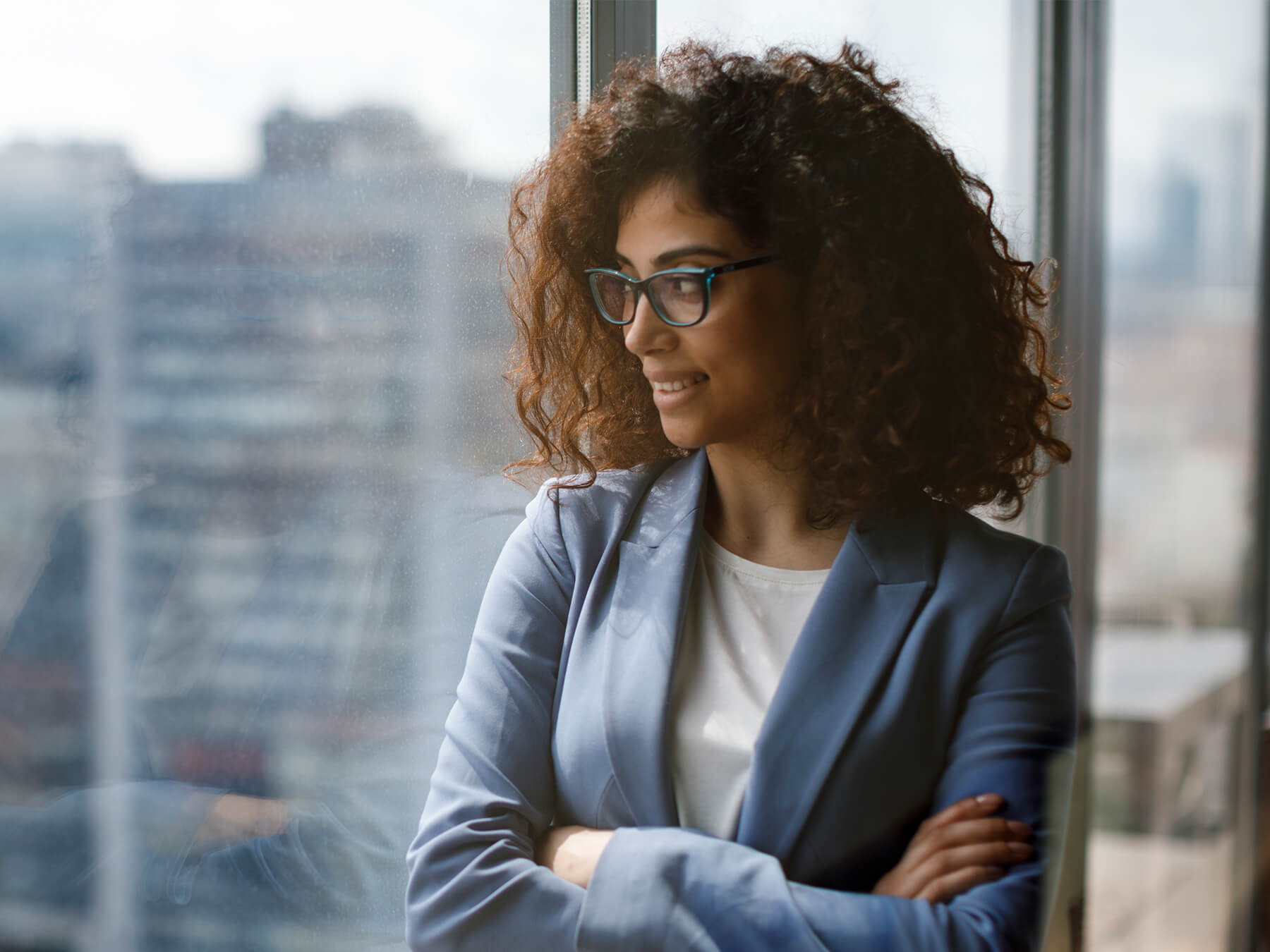 Professional female CPA looks out office hi-rise window