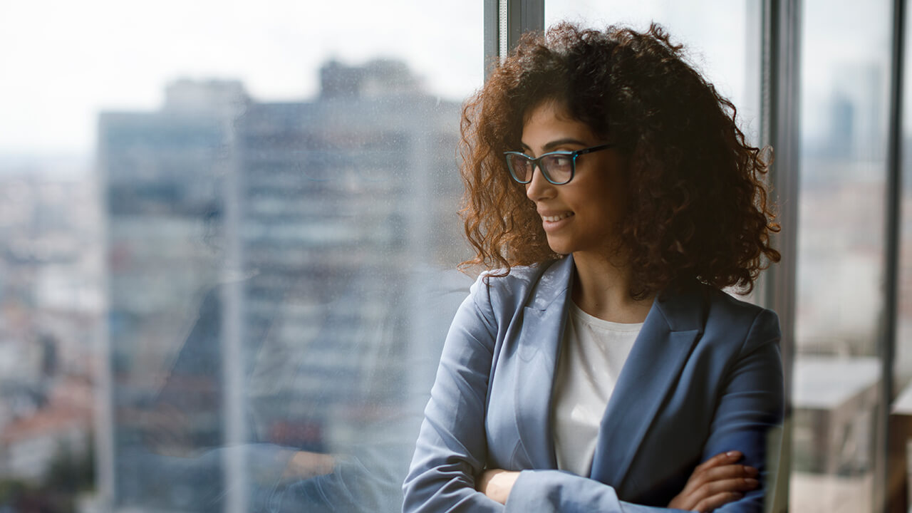 Professional female CPA looks out office hi-rise window